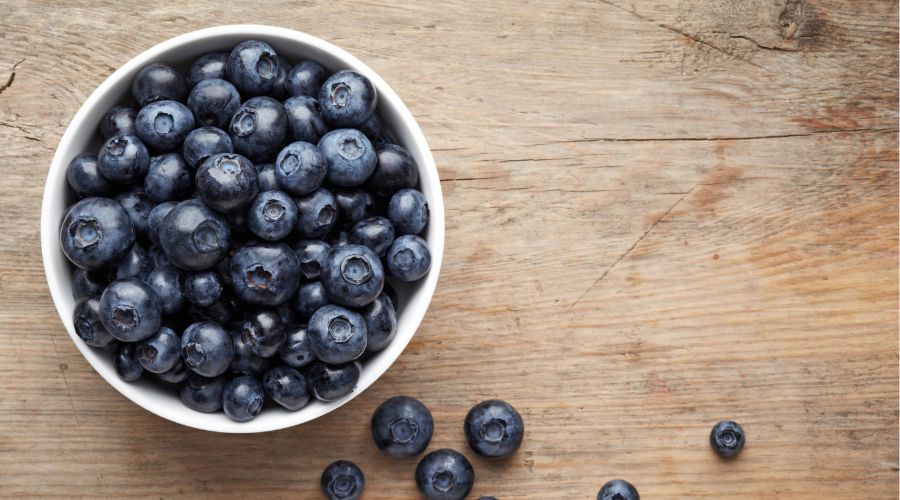 blueberries in a bowl on a wooden table