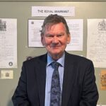 man standing in front of a wall of Royal Warrants