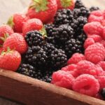 wooden rectangular bowl of strawberries, blueberries, raspberries and blackcurrants