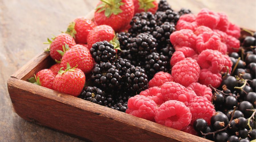 wooden rectangular bowl of strawberries, blueberries, raspberries and blackcurrants